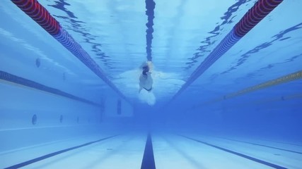 Muscular man under water in a swimming pool in slow motion