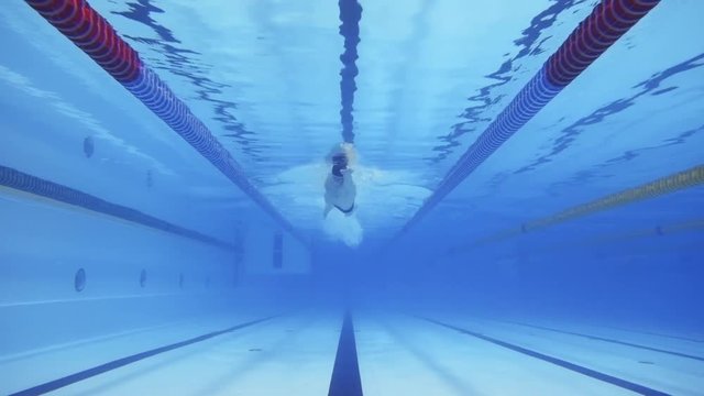 Muscular man under water in a swimming pool in slow motion