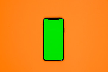 iPhone XS, smartphone, green screen on Orange background top view