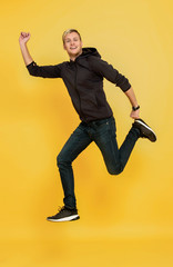 Fototapeta na wymiar portrait of an excited man jumping while celebrating success over yellow background.