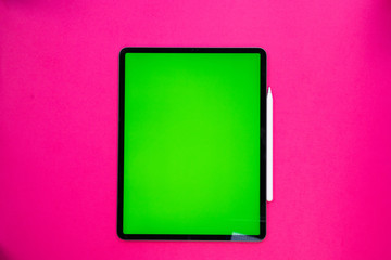 new tablet on a Pink background with a keyboard and pen, and green screen top view