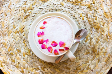 Cup pink cappuccino with foam decorated with rose petals wattled napkin spoon. Top vveiw. Cozy design