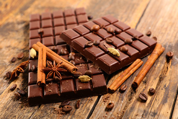 chocolate bar with spices on wood background