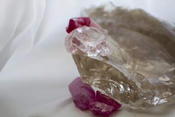 background of a large transparent quartz crystal and purple crystals on a white blurred background