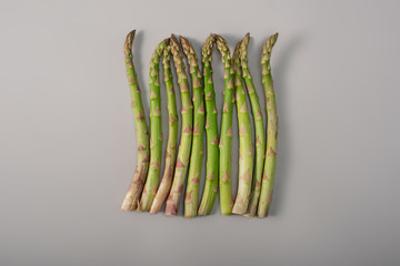 top view of green organic raw asparagus in row on grey background