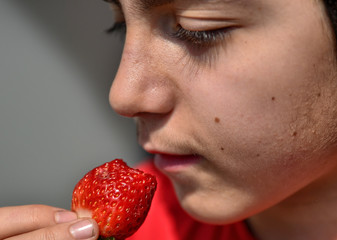 Caucasian child who is eating a strawberry