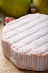 Round piece of French cheese Fleur Rouge made from cow milk served as dessert with fresh figs and pears