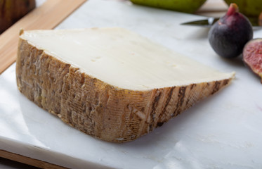 Piece of French cheese Tomme de Brebis made from sheep milk served as dessert with fresh figs and pears