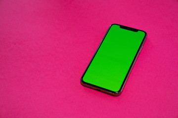 iPhone, smartphone, green screen on Pink background top view
