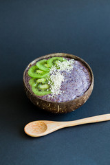 Healthy smoothie , plate made from coconut shell on dark background