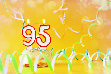 Ninety five years birthday. Cupcake with burning candles in the form of number 95. Bright yellow...
