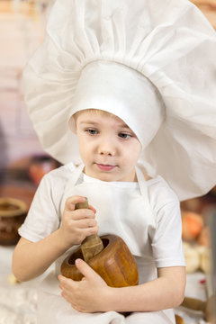 the little boy is preparing cake and pancakes. Dressed like a chef child dough prepares food. 