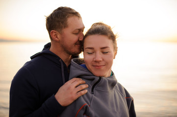 Young man kissing his girlfriend standing from behind