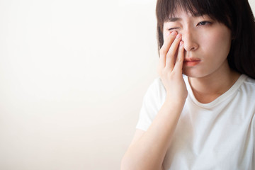 Asian​ woman​ suffering​ from​ eyes pain​ and​ feeling something in​ her eye.​ Cause of pain include contact lens problem, conjunctivitis, foreign object, dry eye syndrome or allergy. Copy​ space.