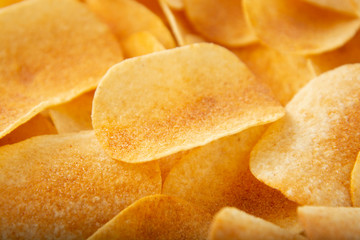 Background golden potato chips texture. Crispy unhealthy snack isolated.