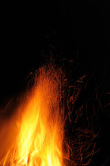 Fototapeta na wymiar Flame of a burning fire with sparks in the night on a black background. Close-up