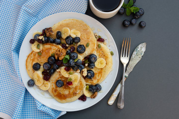 Pancakes and coffee with blueberries, mint, fruits and honey for breakfast - homemade healthy food. Breakfast idea.