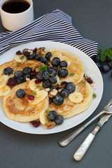 Freshmade, homemade pancakes with blueberry, dried fruits and honey. Breakfast with coffee and pancakes. Deliciious healthy food.