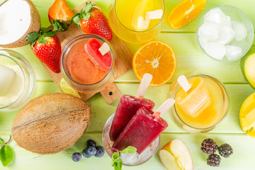 Selection of colourful ice pops and ingredients on green wood background