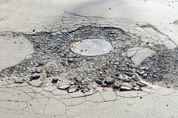 Destroyed asphalt pavement around sewer hatch
