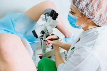 Naklejka na ściany i meble Treatment of cervical disease. Female gynecologist Unrecognizable woman patient in gynecological chair during gynecological check up. Gynecologist examines a woman. Diagnostic, medical service.