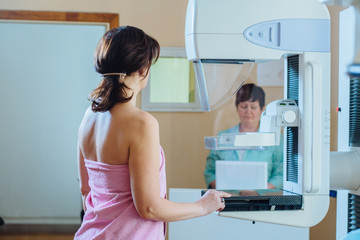 Fototapeta na wymiar Female patient under going mammography test in hospital. Back view, selective focus