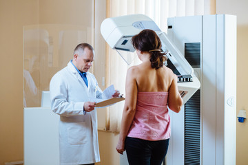 Male doctor mammologist holding application form while consulting female patient. Breast cancer...
