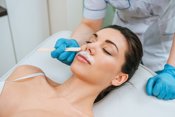 Partial view of cosmetologist in rubber gloves doing alkaline depilation