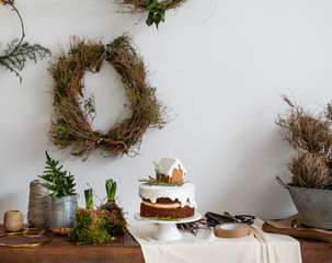 Weihnachtliche Torte aus Lebkuchen mit kleinem Haus und Zuckerguss  in dekorierter Ungebung