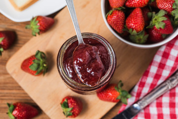 Jar of strawberry jam on  wooden background from top view