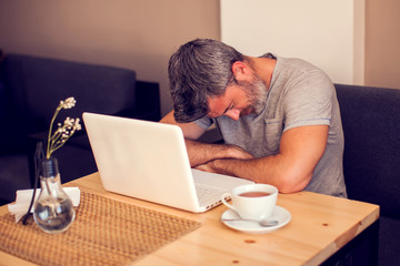 Man having a headache in front of laptop