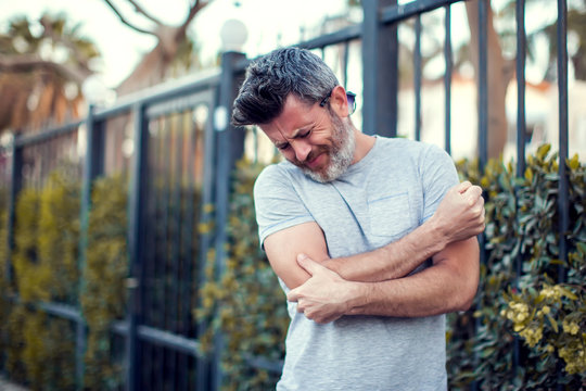 Man Feeling Elbow Pain On The Street