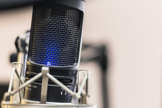 Close up Condenser microphone on holder with blue light swith on and copy space on white background