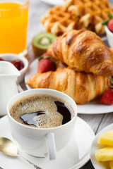 Continental breakfast table with coffee, orange juice, croissants