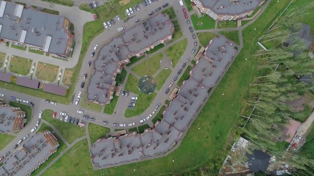 Shooting a residential area with low-rise buildings, roads on which cars go, aerial photography, the camera moves away from the object on a summer day