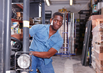 Fototapeta na wymiar African American worker of building materials warehouse working on forklift truck