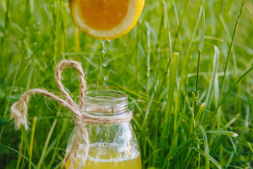 male hand squeezes citrus fruit juice into a bottle of homemade lemonade on the grass on the nature outdoors. close-up, healthy food, diet, proper nutrition, picnic.