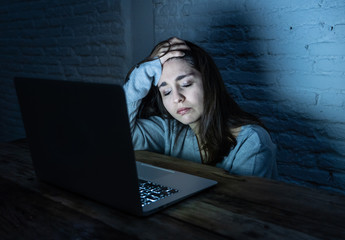 Scared woman on laptop in the dark feeling fear suffering online harassment and cyberbullying