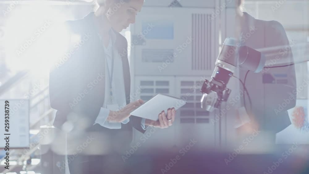 Fototapete stylish female industrial robotics engineer uses tablet computer to program and manipulate robot arm