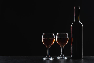 Bottles of wine and different glasses of wine on a dark background