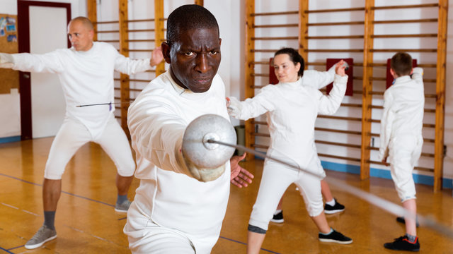African American fencer practicing effective fencing techniques in training room