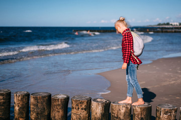 Young cure girl walking on the breakwater at the coast of the Baltic sea. 