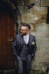 Portrait of a handsome groom in a grey suit with a tie and vest.