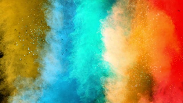 Super slowmotion shot of color powder explosions isolated on black background.