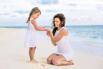 Mother with little daughter playing on ocean beach, Maldives