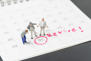 Happy retirement, wealth plan for life after retire from work concept, group of miniature happy senior old men standing with circle on white calendar with handwriting the word retire