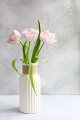 Pink tulips in vase on grey background
