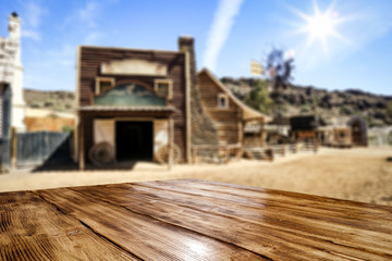 Fototapeta na wymiar Wooden old table of free space for your product. Blurred background of Wild West city in America. 
