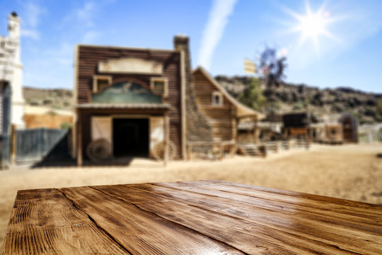 Wooden old table of free space for your product. Blurred background of Wild West city in America. 