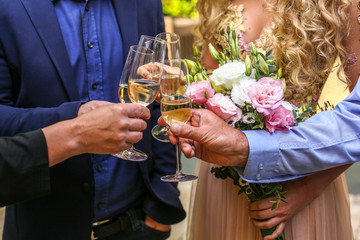 Bridal couple holding champagne and wedding bouquet
